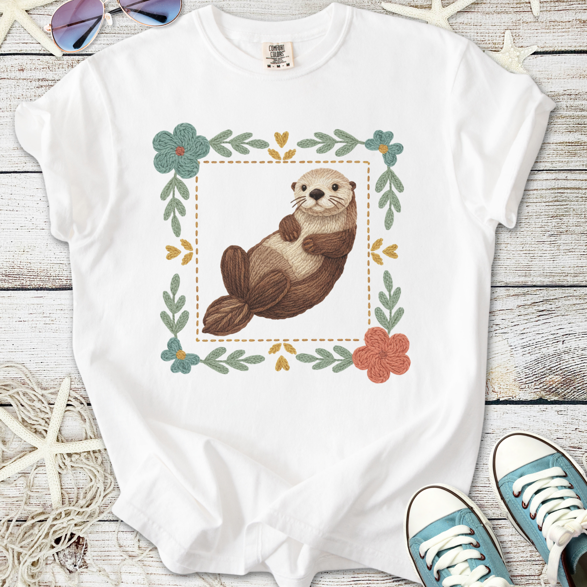 Cute white t-shirt featuring an illustrated otter surrounded by floral designs, perfect for casual wear.