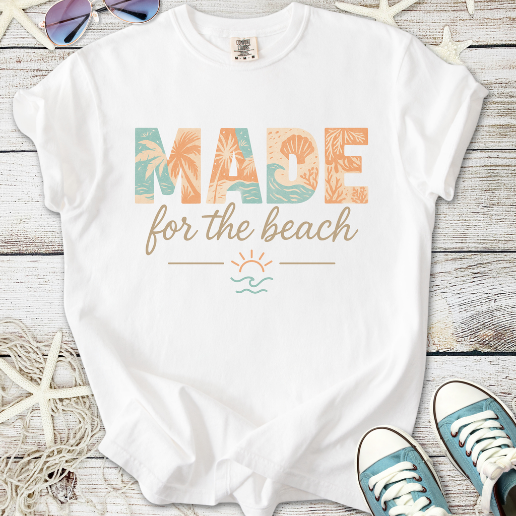 White t-shirt with 'MADE for the beach' graphic, featuring coastal colors and tropical designs.
