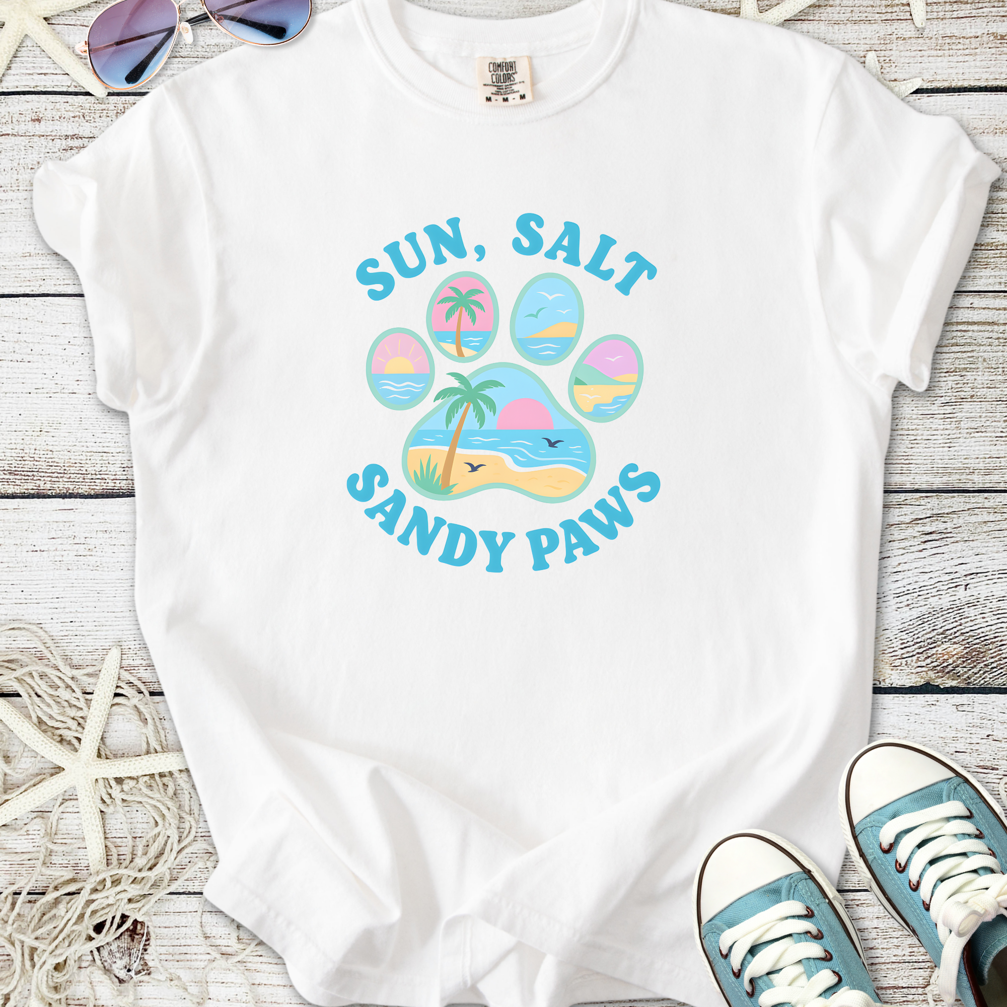 White t-shirt featuring 'Sun, Salt, Sandy Paws' beach-themed graphic design, perfect for summer outings.