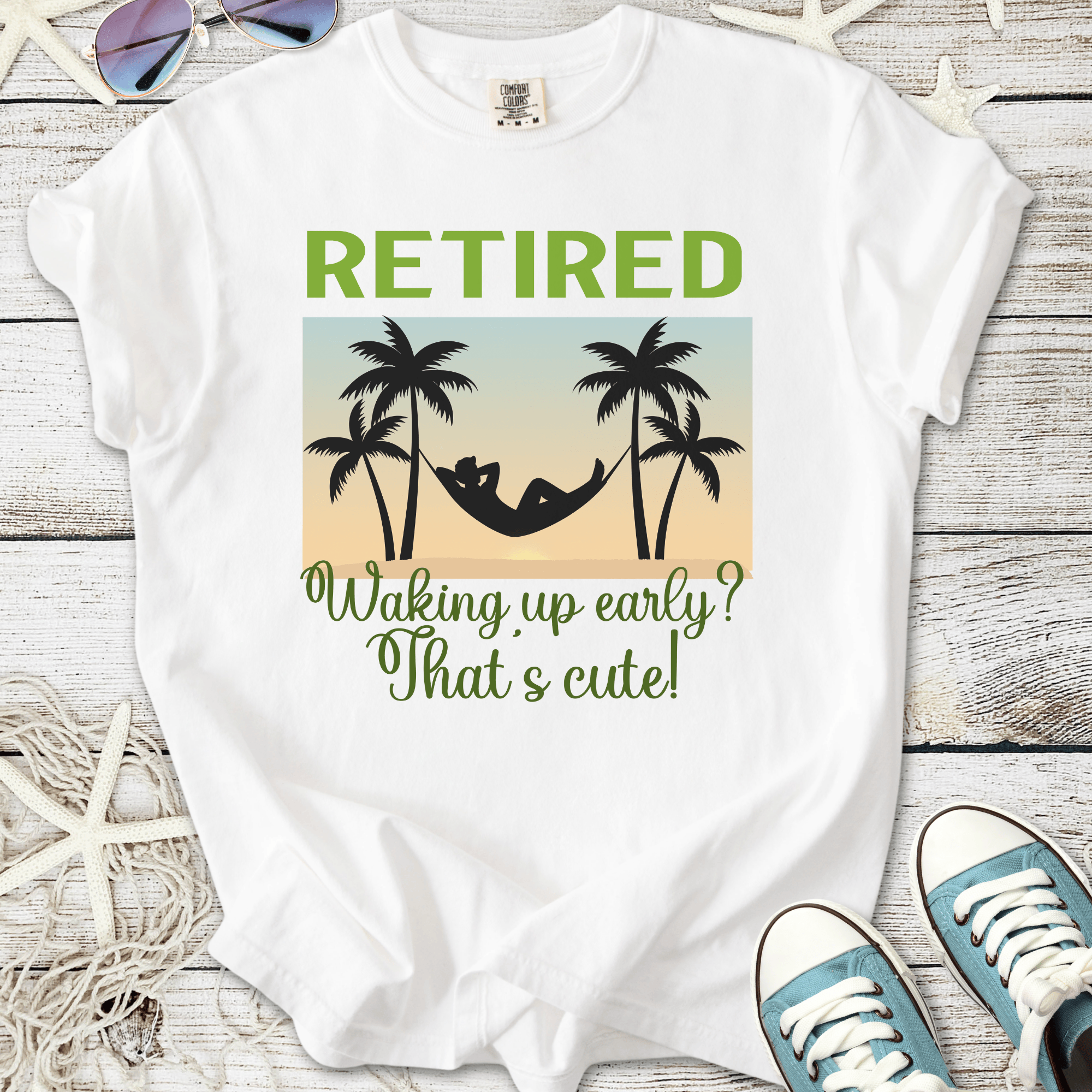 White t-shirt featuring 'Retired' graphic with palm trees and hammock design, perfect for relaxation.
