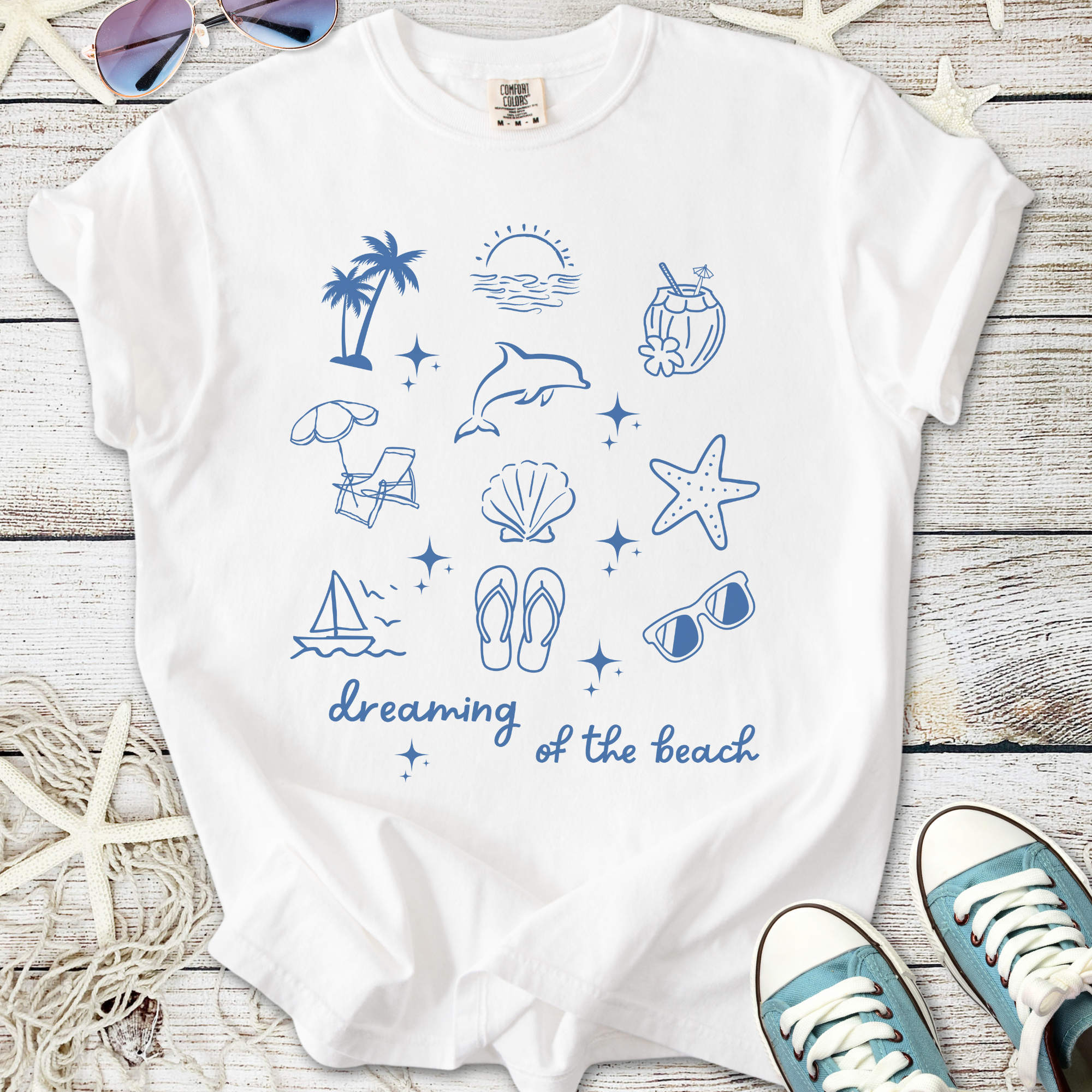 White t-shirt with beach-themed blue graphics, featuring palm trees, dolphin, and starfish.