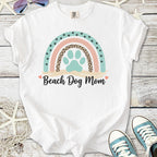 White t-shirt with colorful 'Beach Dog Mom' graphic and paw print design, perfect for dog lovers.