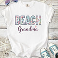 White cotton t-shirt with 'BEACH Grandma' graphic, colorful coral design, perfect for beach lovers.
