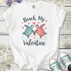 White t-shirt with 'Beach My Valentine' graphic featuring cute turtles and hearts.