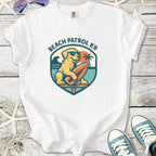 White 'Beach Patrol K9' t-shirt featuring a dog on a surfboard, perfect for beach lovers.