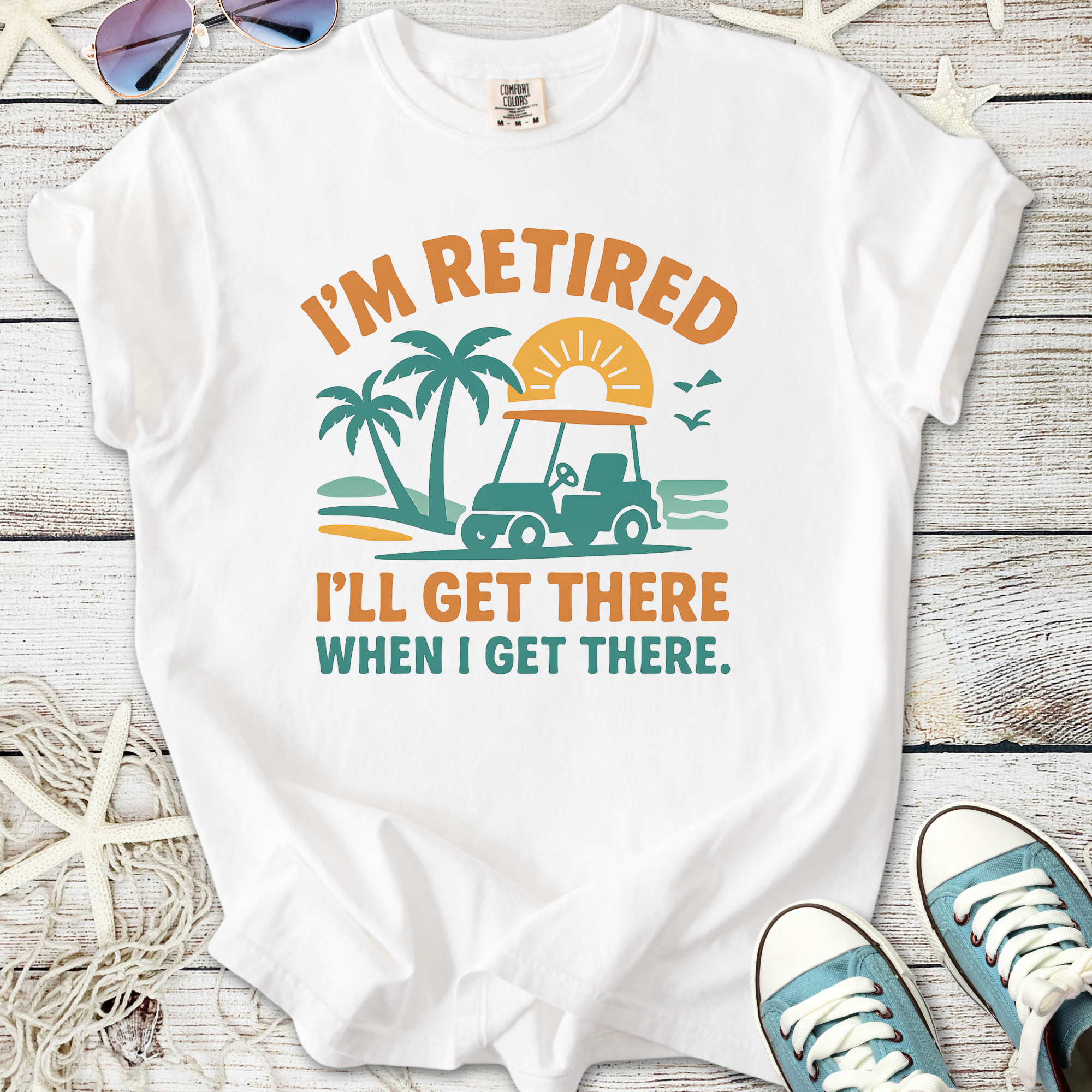 White t-shirt with 'I'm Retired, I'll Get There When I Get There' print featuring a golf cart and palm trees.