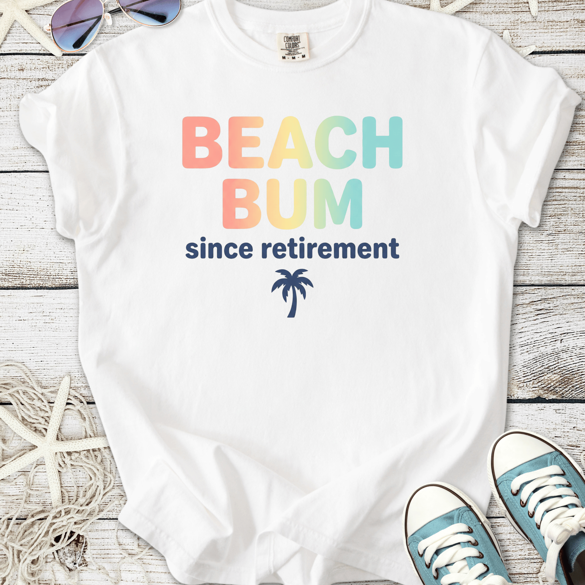 White t-shirt with 'BEACH BUM since retirement' text and palm tree design, ideal for beach lovers.