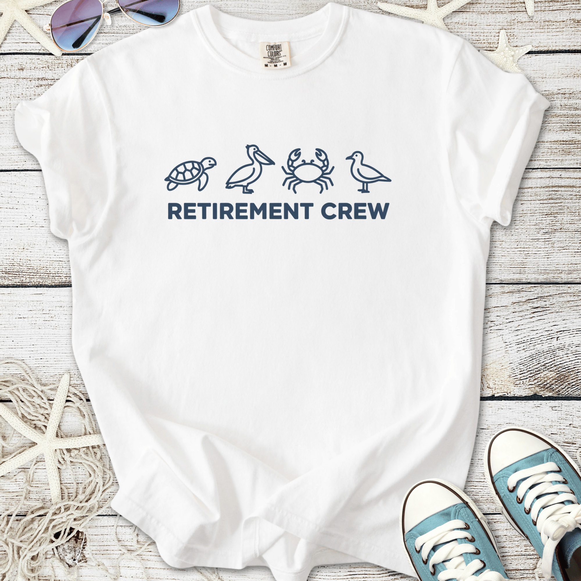 White t-shirt with 'RETIREMENT CREW' text and marine animal graphics, perfect for casual wear.