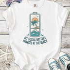 White t-shirt featuring beach-themed graphic 'My Social Battery Charges at the Beach' with palm and waves.