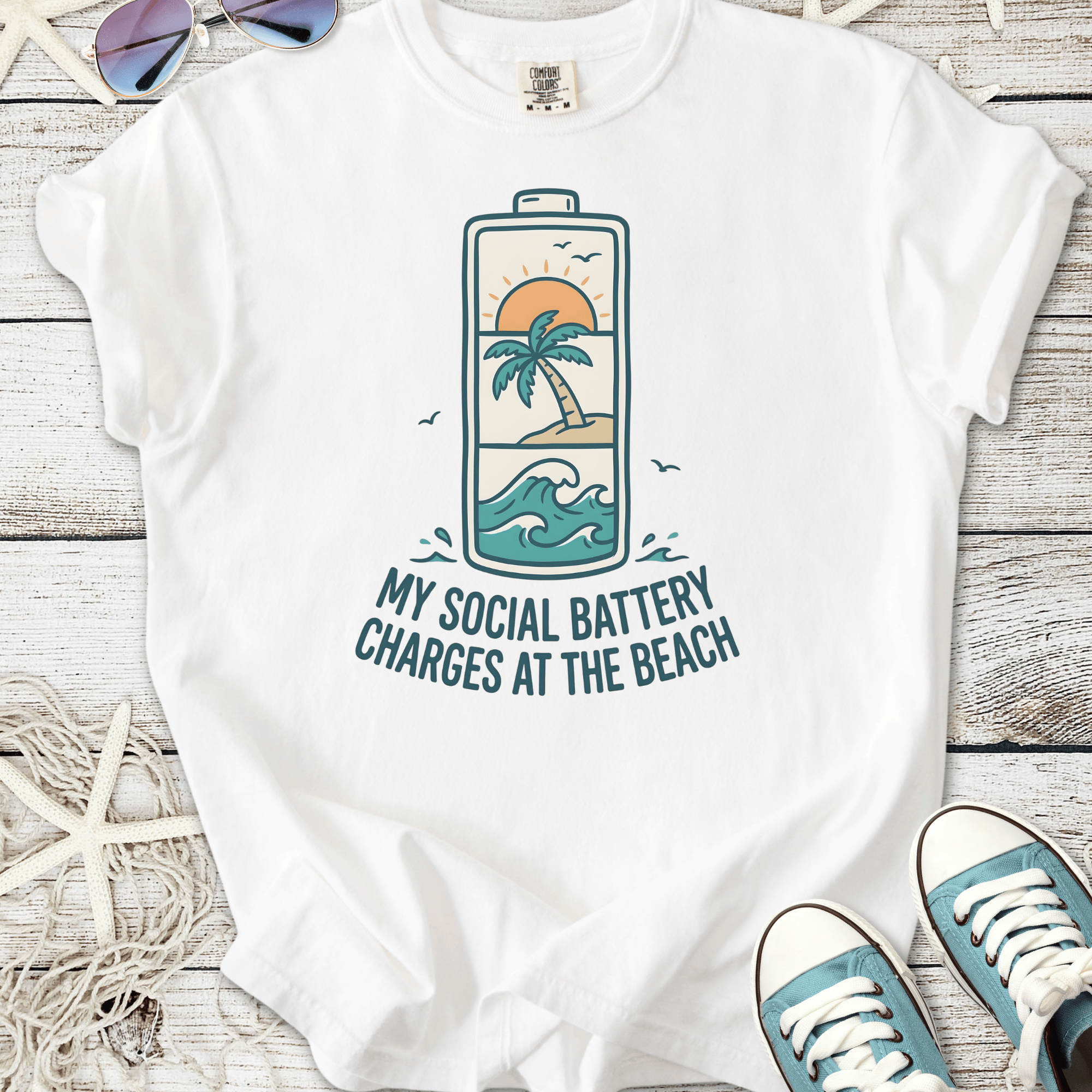 White t-shirt featuring beach-themed graphic 'My Social Battery Charges at the Beach' with palm and waves.