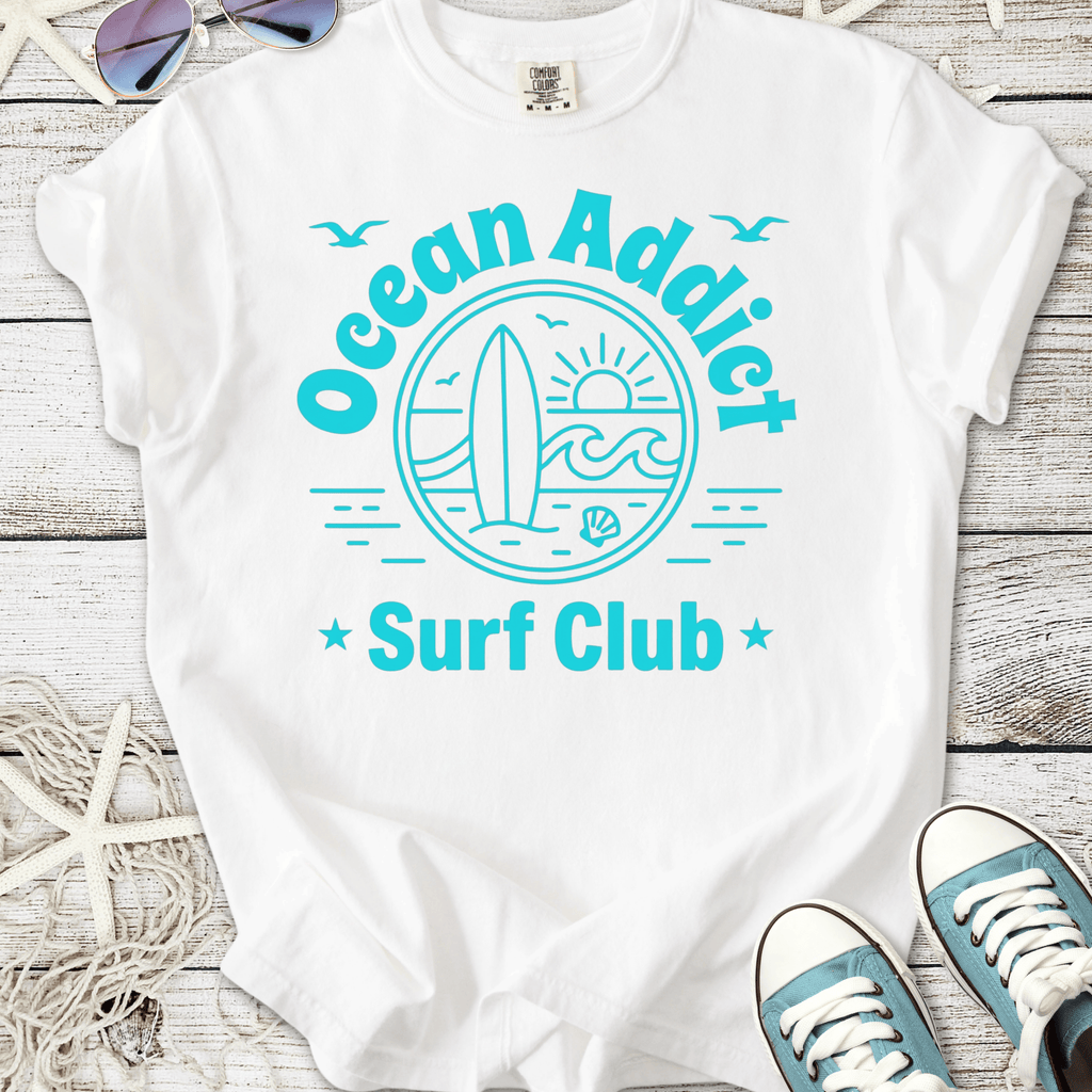 White t-shirt with 'Ocean Addict Surf Club' graphic, featuring a surfboard and ocean design.