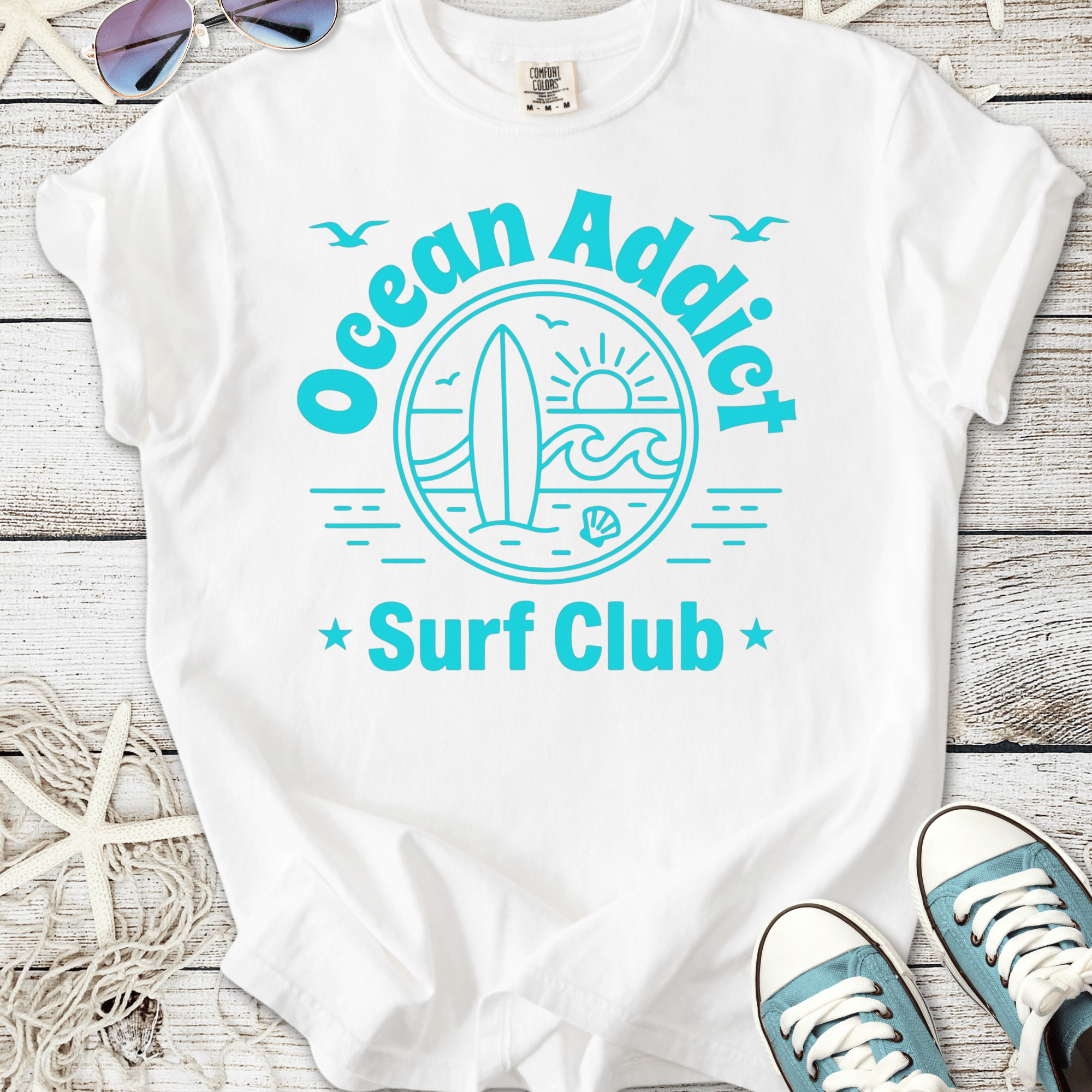 White t-shirt with 'Ocean Addict Surf Club' graphic, featuring a surfboard and ocean design.