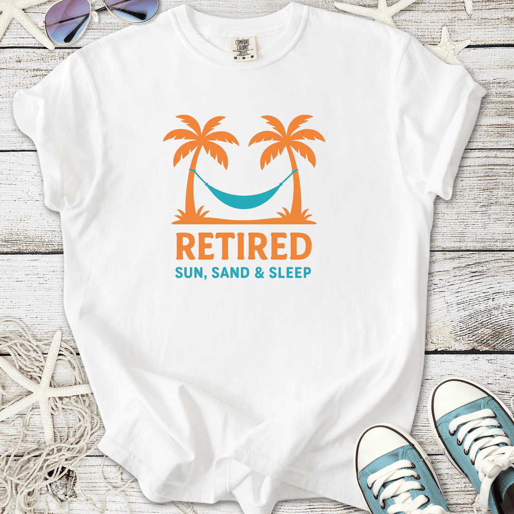 White t-shirt featuring a vibrant design with palm trees, hammock, and 'Retired: Sun, Sand & Sleep' text.