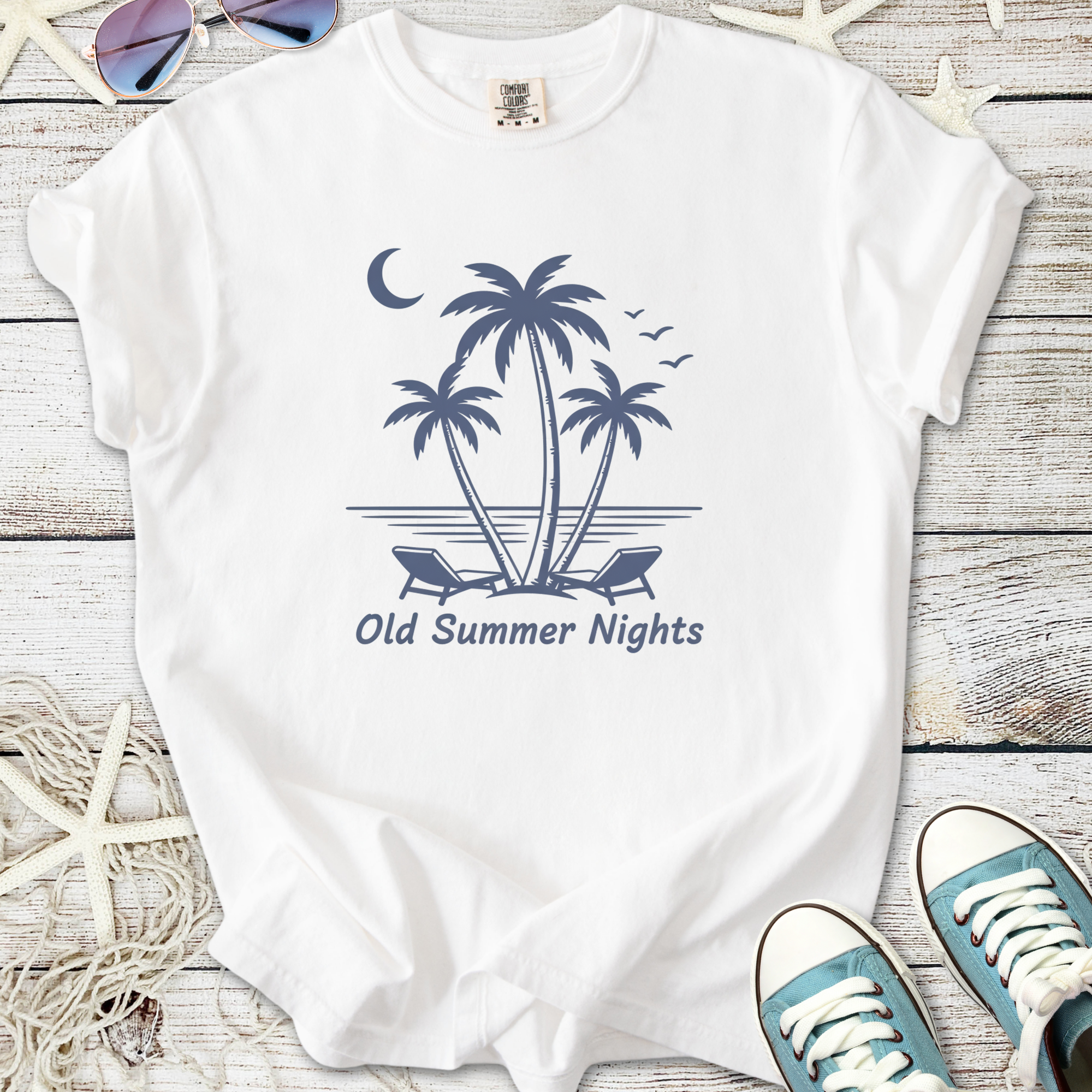 White t-shirt with 'Old Summer Nights' print featuring palm trees and beach chairs, perfect for summer outings.