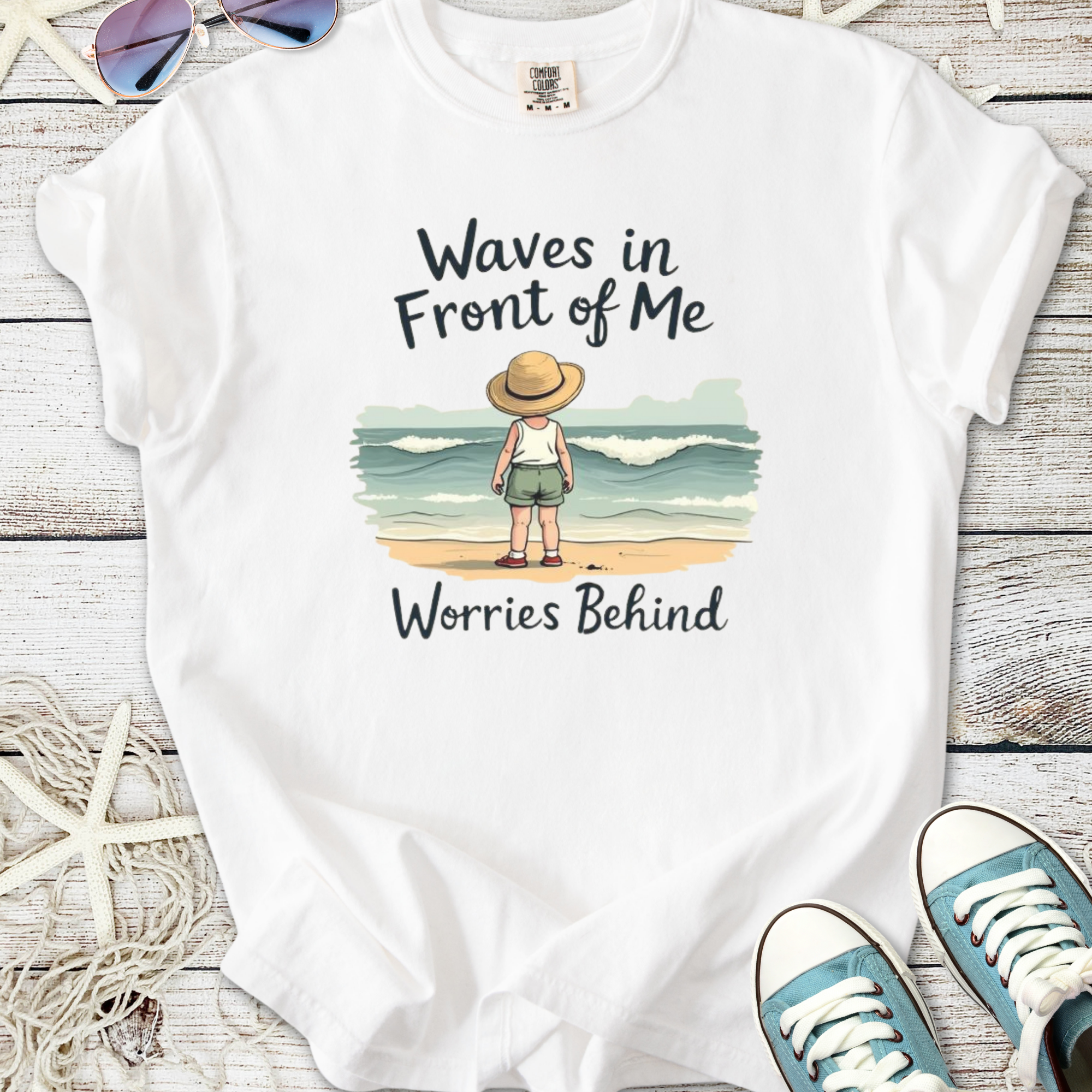 White t-shirt featuring a child with a straw hat, standing by the beach, text 'Waves in Front of Me'.