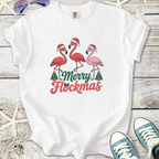 White t-shirt featuring festive flamingos with Santa hats and 'Merry Flockmas' text in vibrant colors.