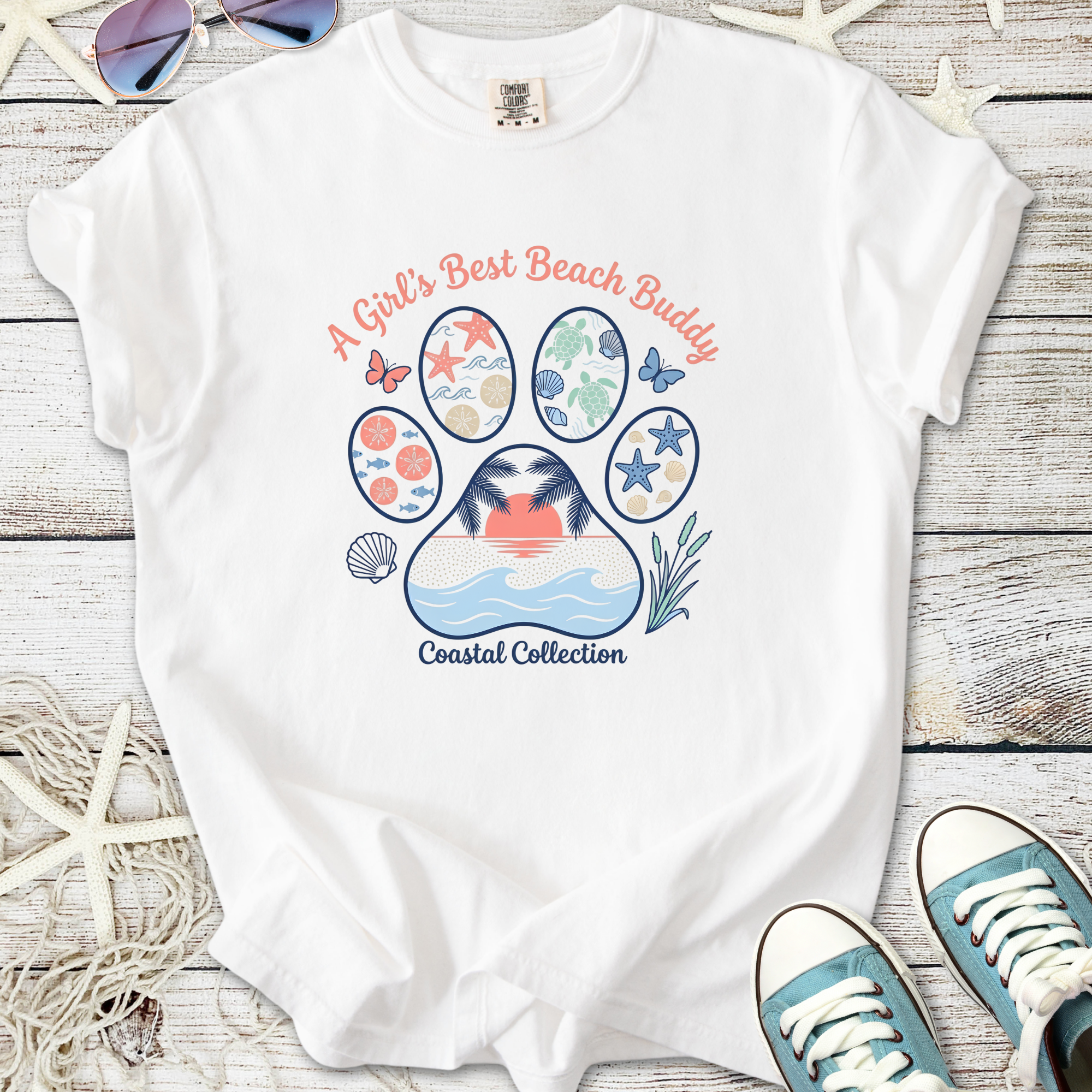 White t-shirt with coastal design, 'A Girl's Best Beach Buddy', featuring seashells and palm trees.