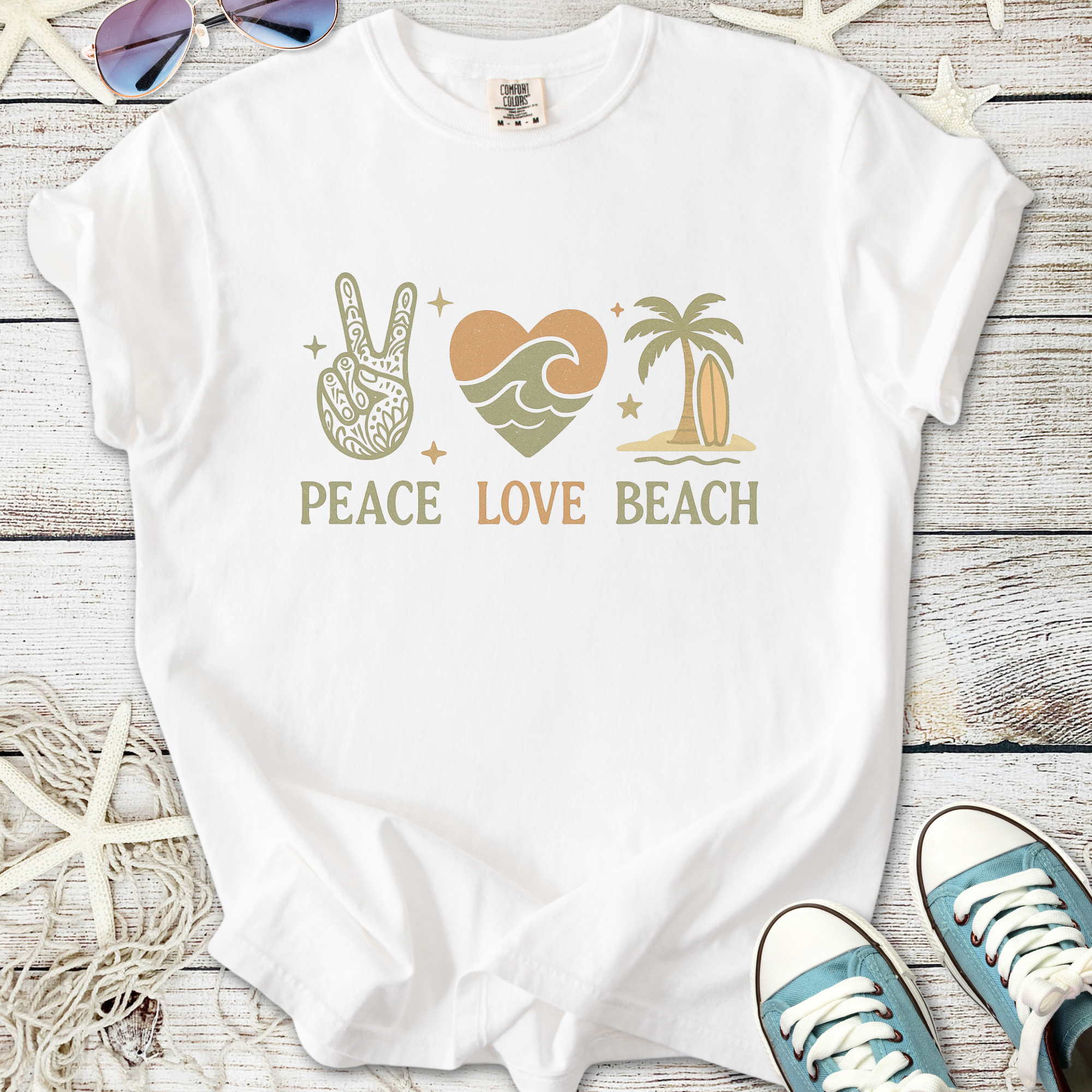 White t-shirt featuring 'Peace Love Beach' graphic with bohemian design elements and tropical colors.