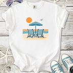 White t-shirt featuring beach scene with chairs, umbrella, sun, and ocean design. Perfect for summer vibes.