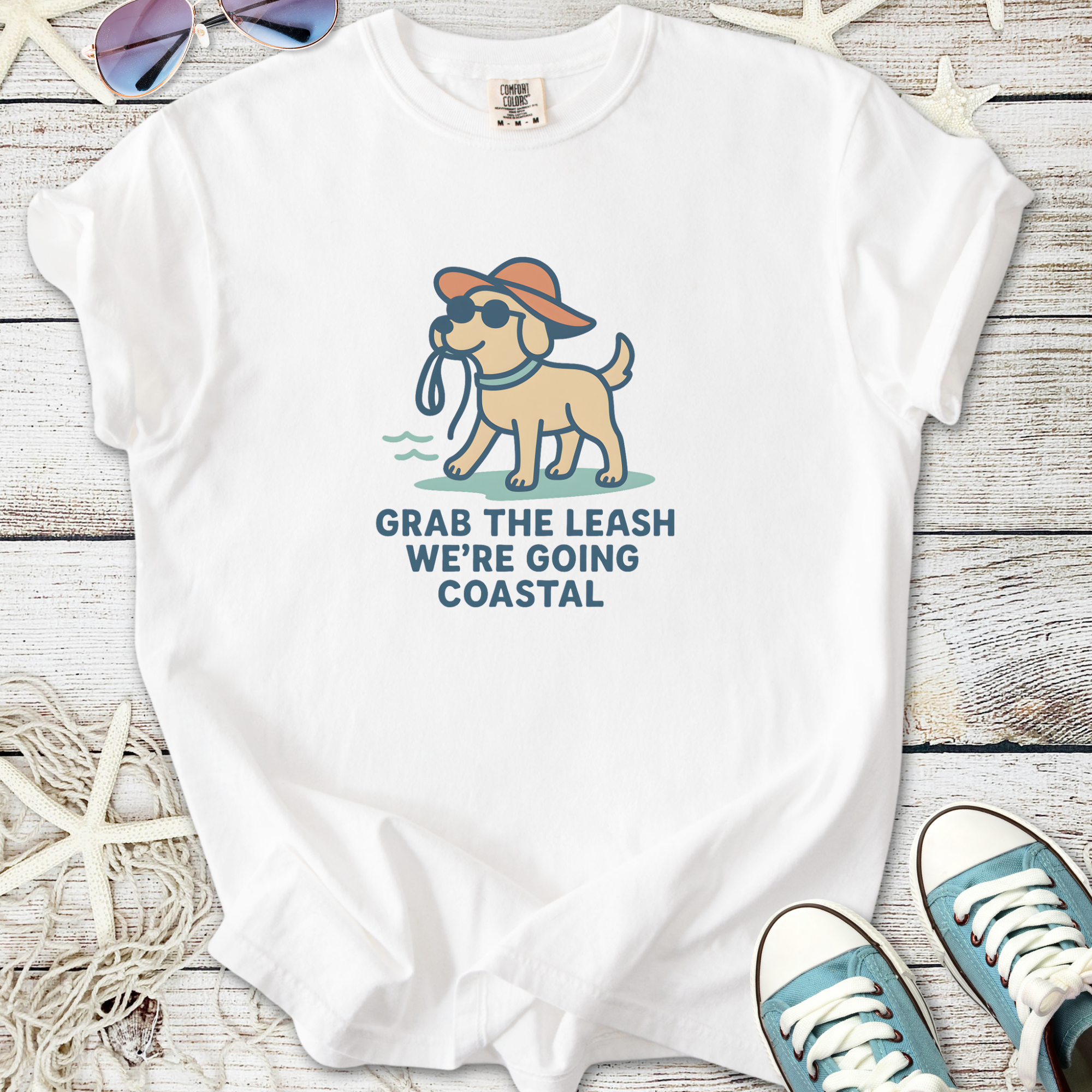 White t-shirt featuring a playful dog graphic with the text 'Grab the Leash, We're Going Coastal'.
