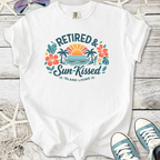 White t-shirt with 'Retired & Sun-Kissed' graphic, featuring tropical designs and vibrant colors.