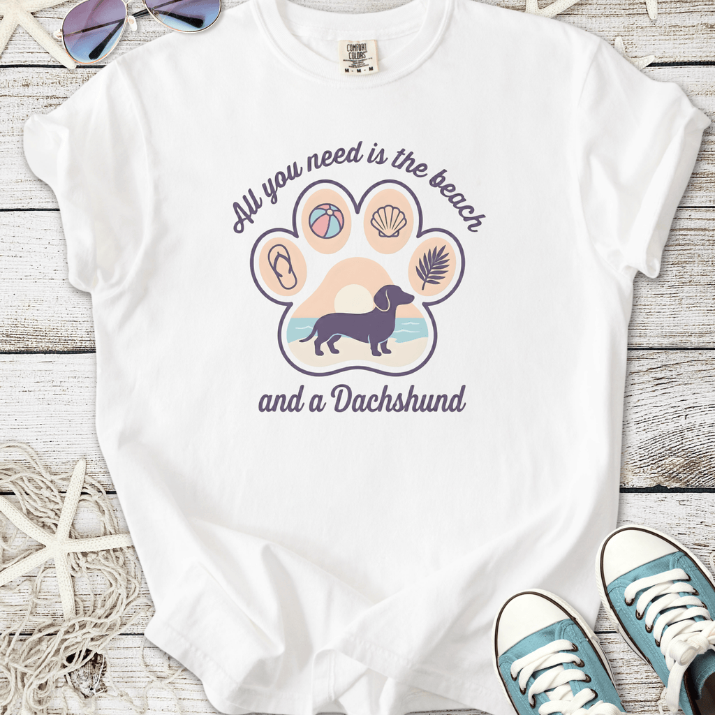 White t-shirt with 'All you need is the beach and a Dachshund' graphic, featuring beach-themed elements.