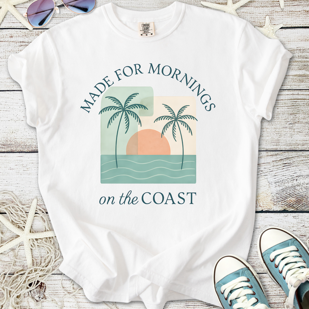 White t-shirt with 'Made for Mornings on the Coast' graphic, featuring palm trees and a sun design.
