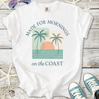 White t-shirt with 'Made for Mornings on the Coast' graphic, featuring palm trees and a sun design.