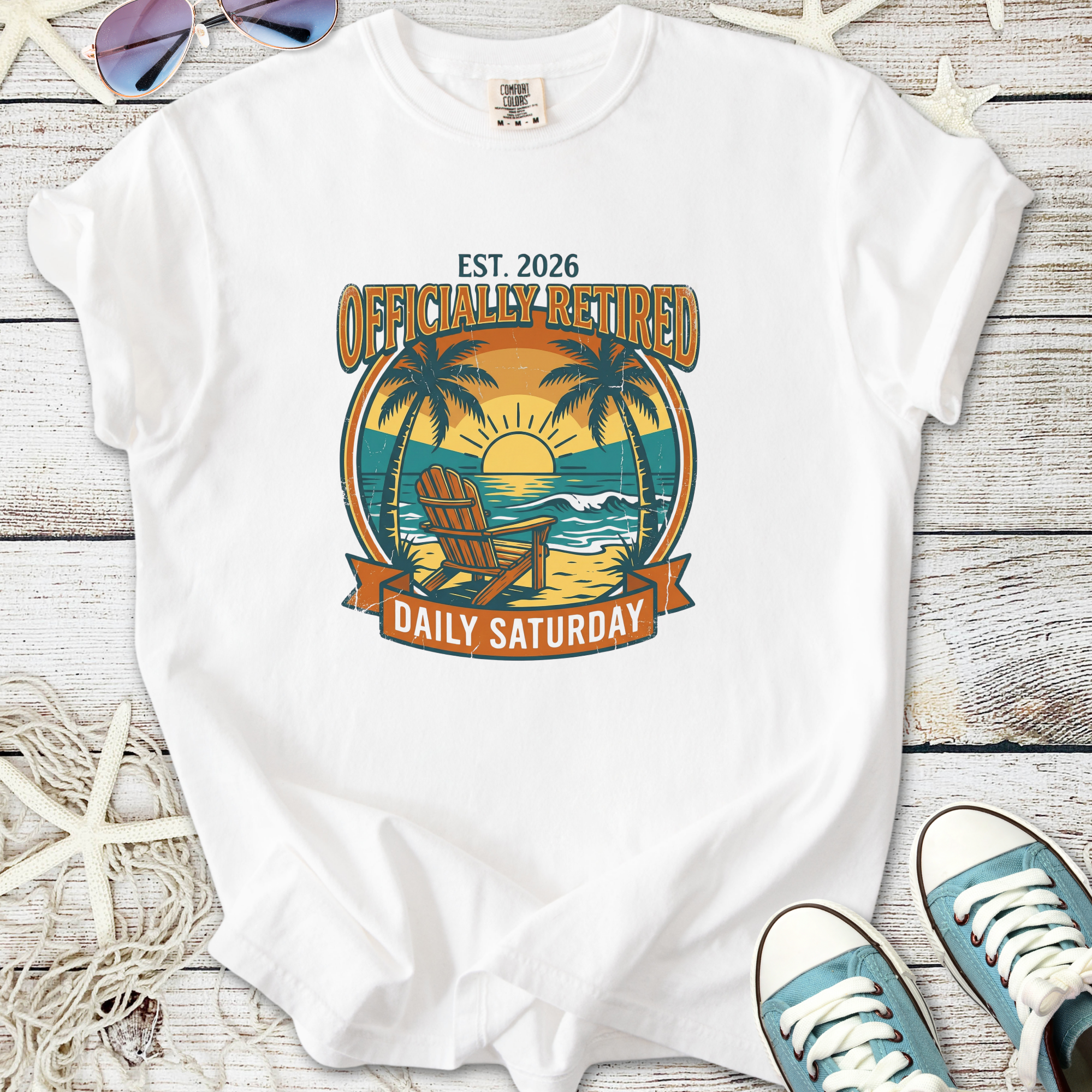 White t-shirt featuring 'Officially Retired' graphic with beach, palm trees, and sunset design.