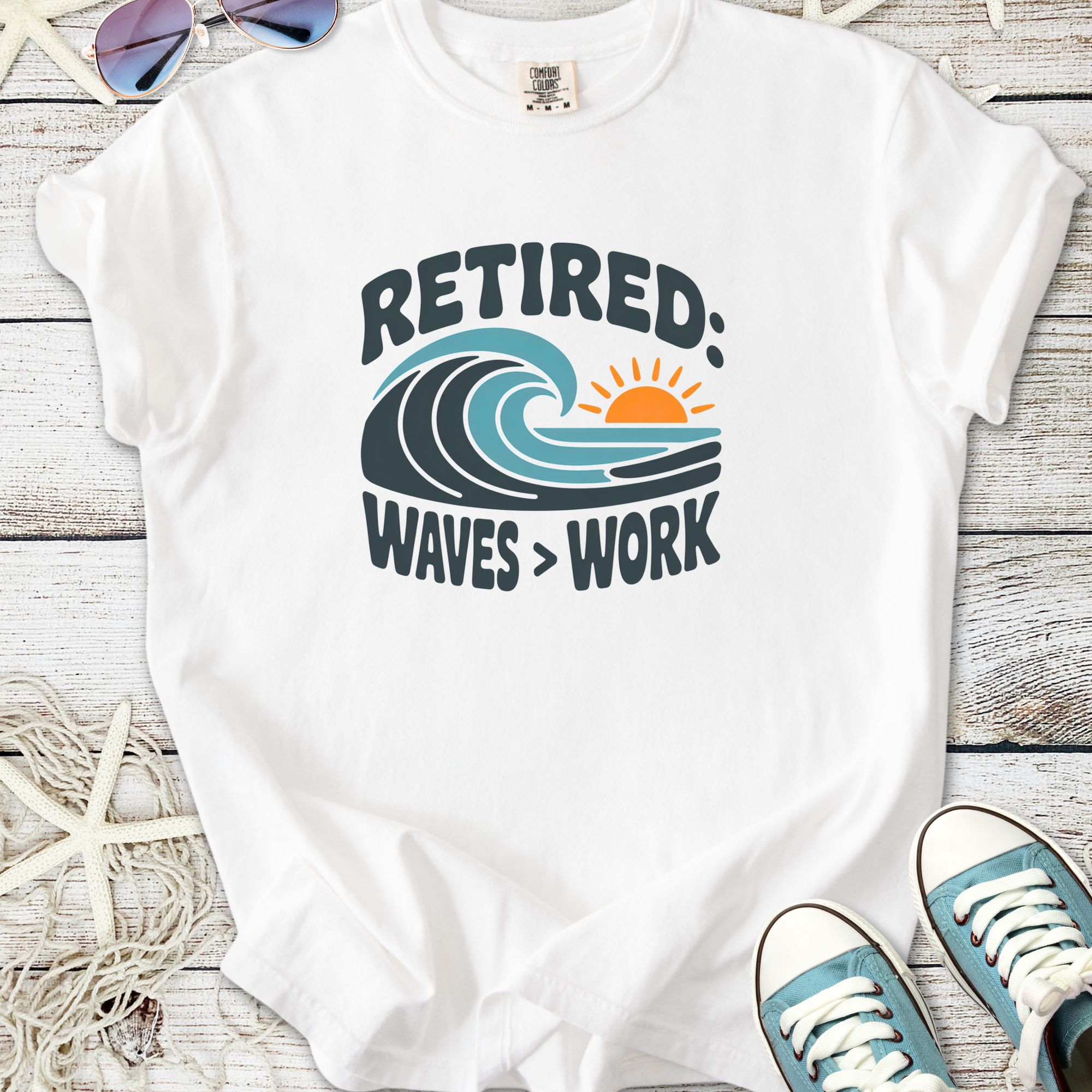 White t-shirt with 'Retired: Waves > Work' graphic design, featuring a wave and sun illustration.