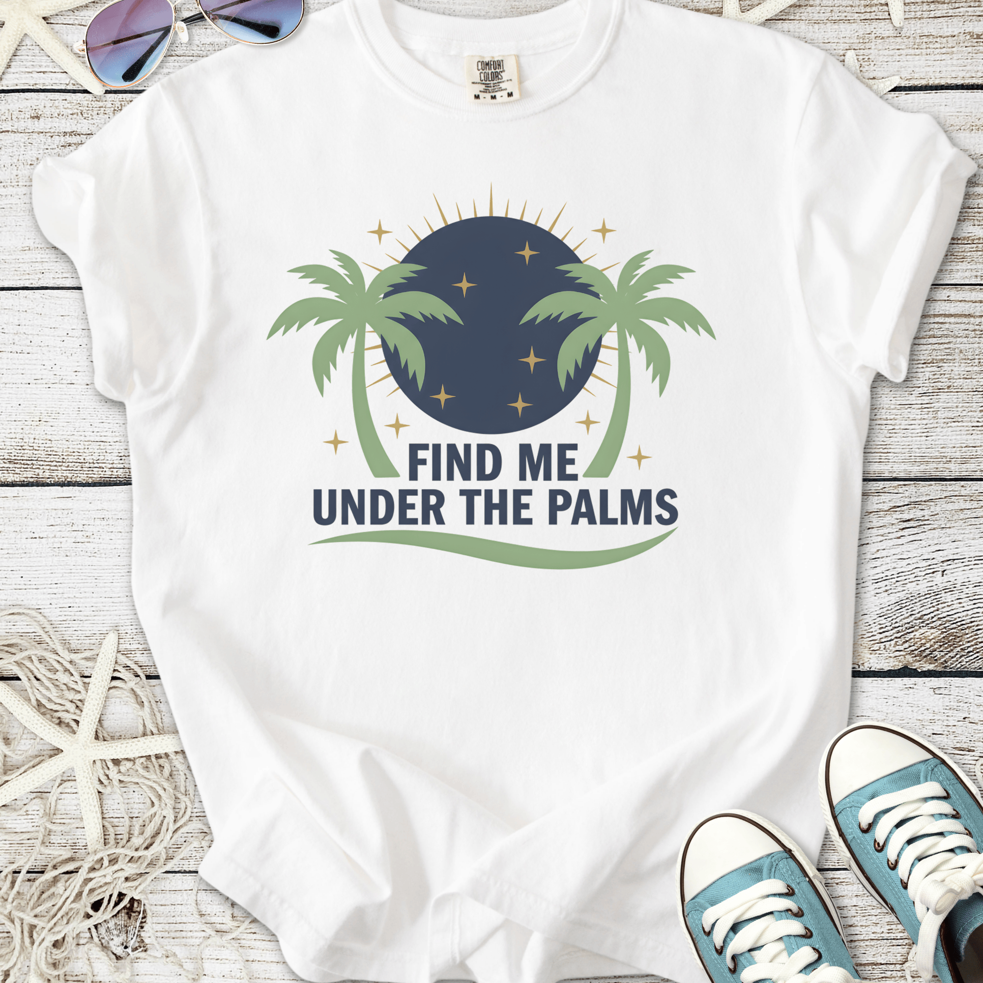 White t-shirt with 'Find Me Under The Palms' graphic, featuring palm trees and a night sky design.