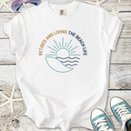 White t-shirt featuring 'Retired and Living the Beach Life' graphic with sun and waves design.