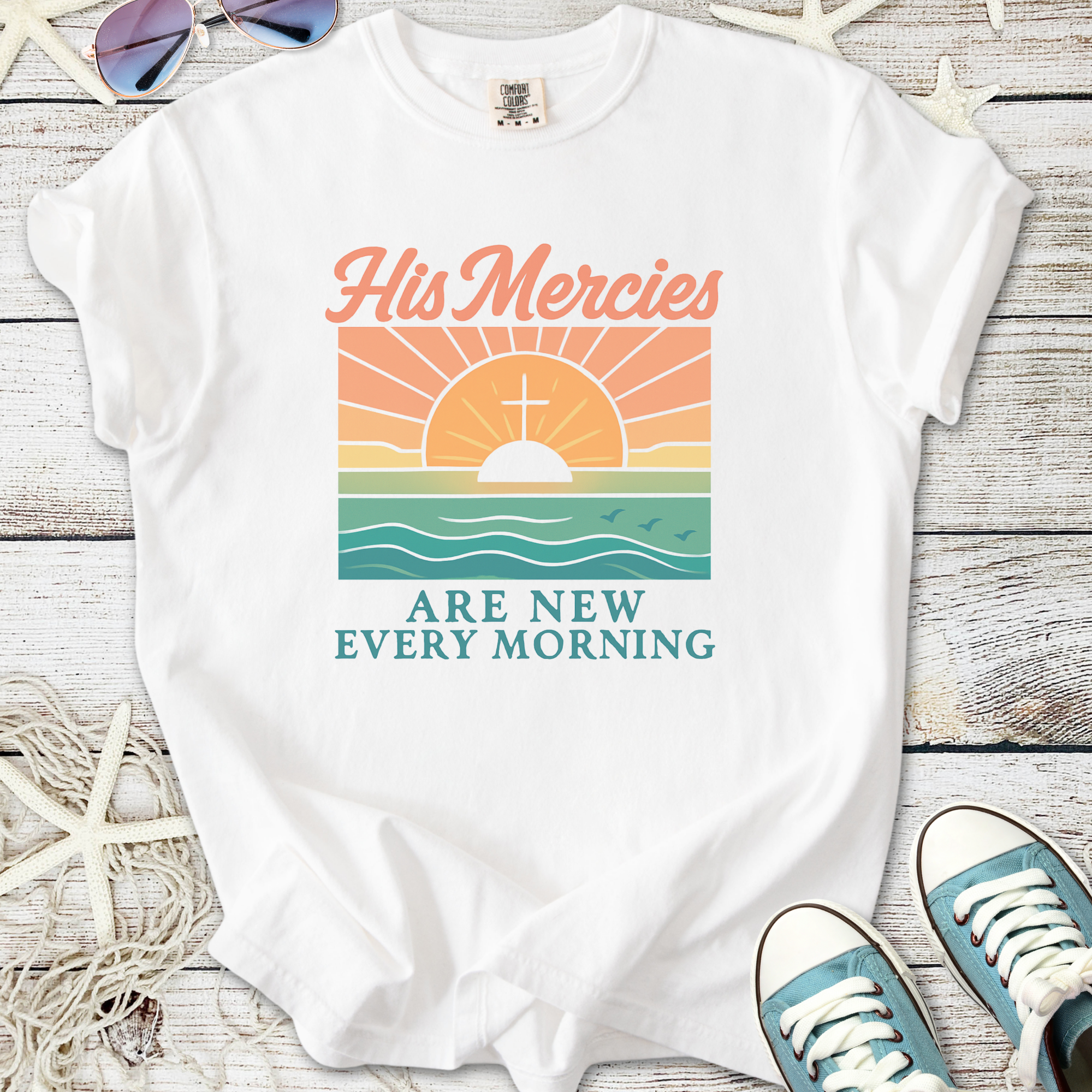 White graphic t-shirt featuring sunrise design with text 'His Mercies Are New Every Morning'.