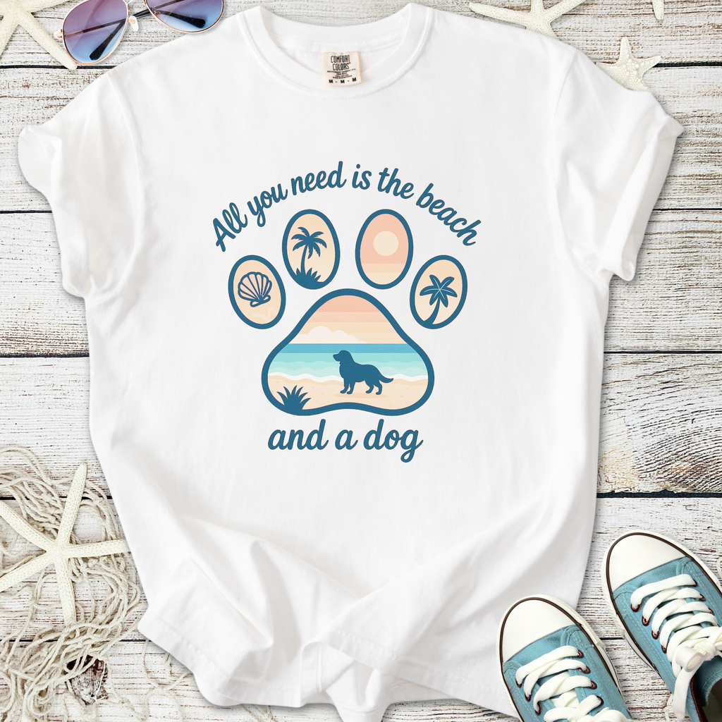 White t-shirt with palm tree, shell, and beach dog graphic. Text: 'All you need is the beach and a dog'.