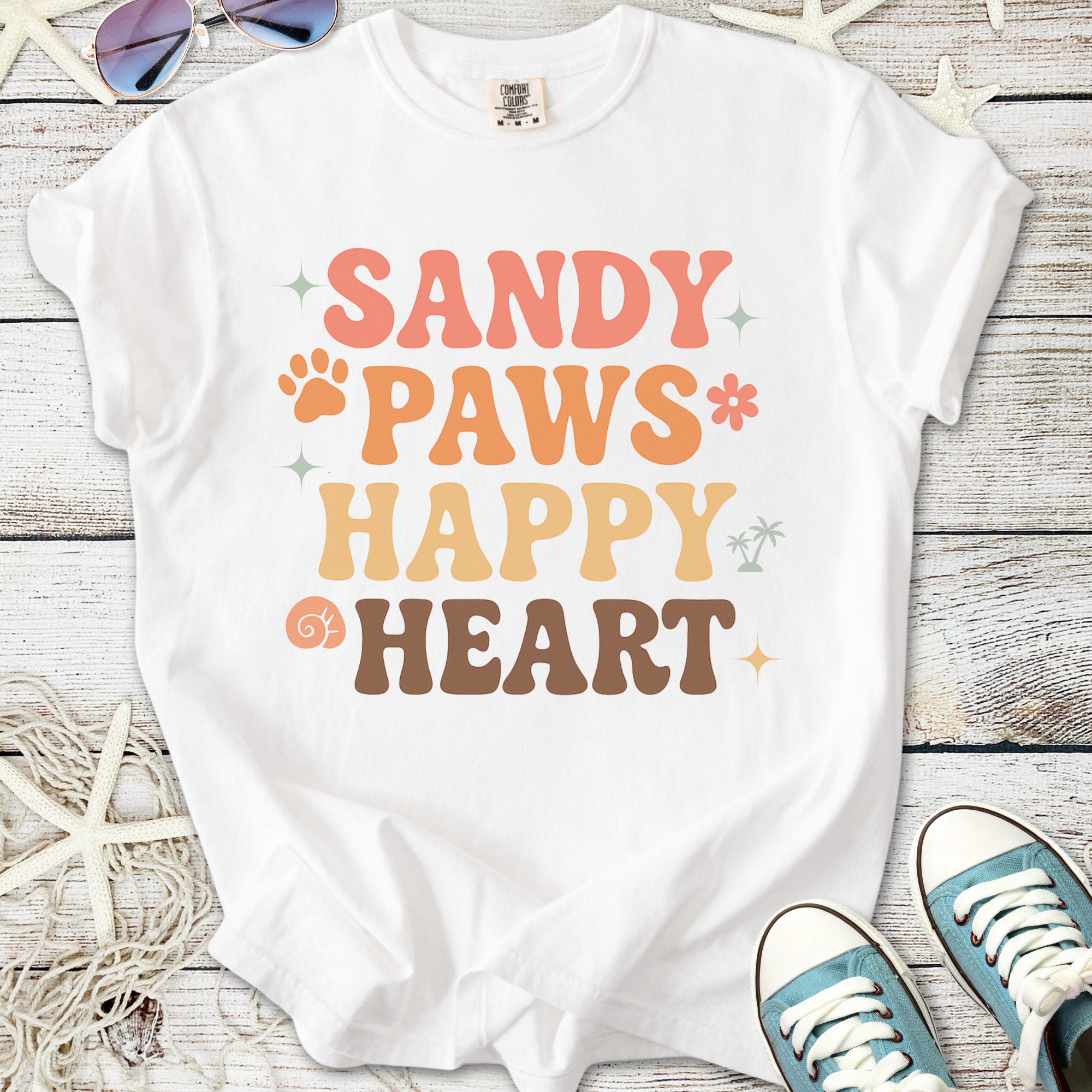 White t-shirt with colorful 'Sandy Paws Happy Heart' graphic, perfect for casual beach outings.