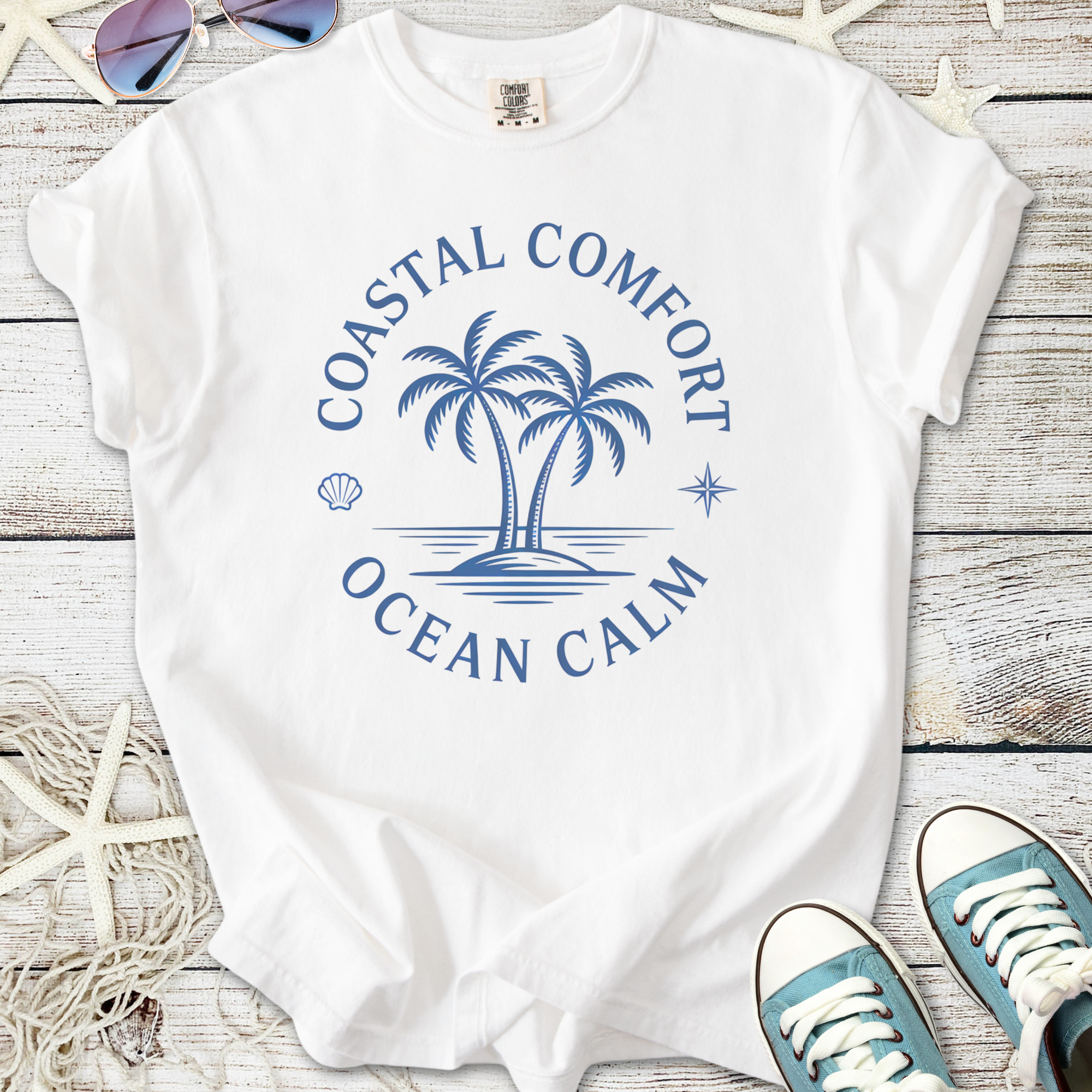 White t-shirt featuring 'Coastal Comfort Ocean Calm' graphic with palm trees, perfect for beach wear.