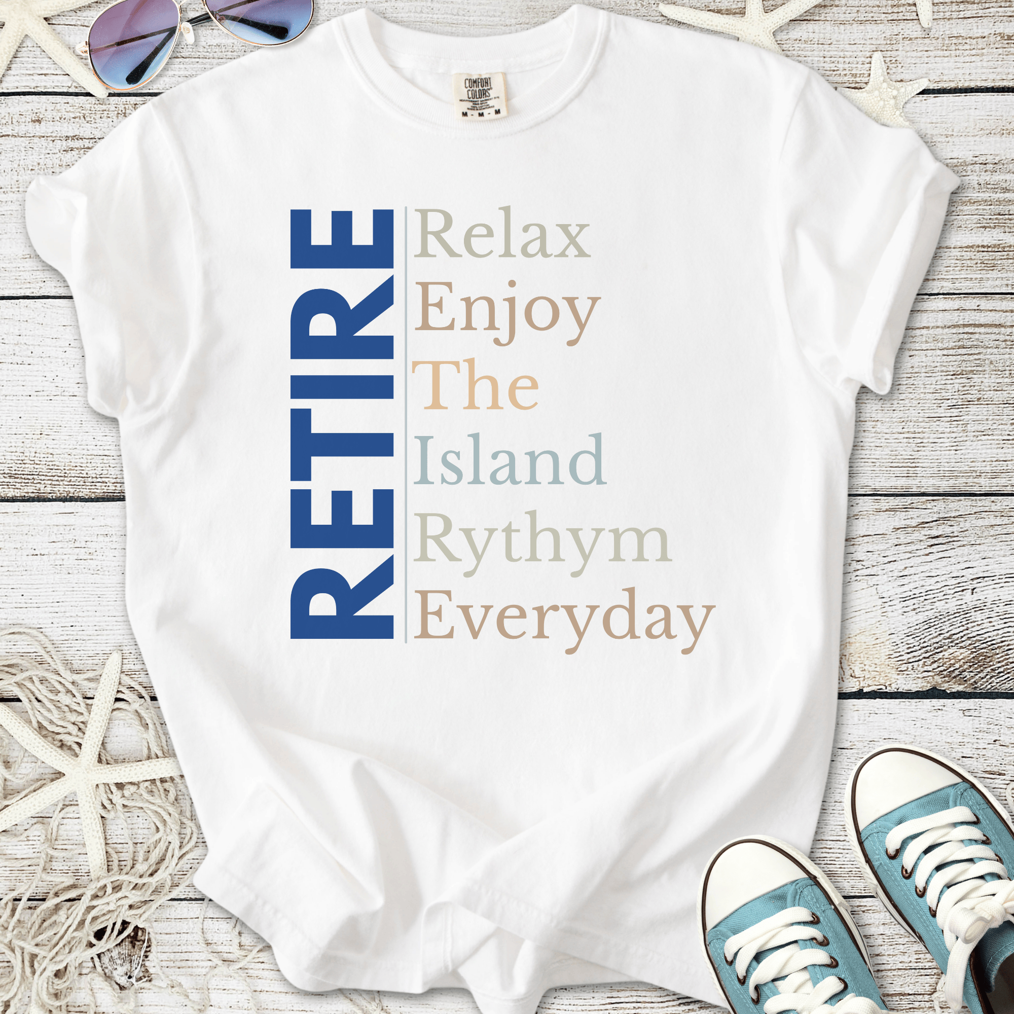 White t-shirt with 'RETIRE' graphic, featuring relaxed island-themed text in blue and pastel colors.