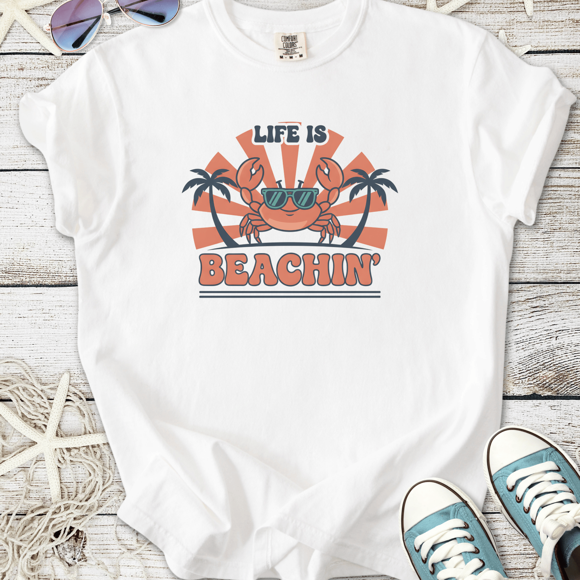 White graphic t-shirt featuring a crab, sunglasses, and text 'Life is Beachin' with palm trees.