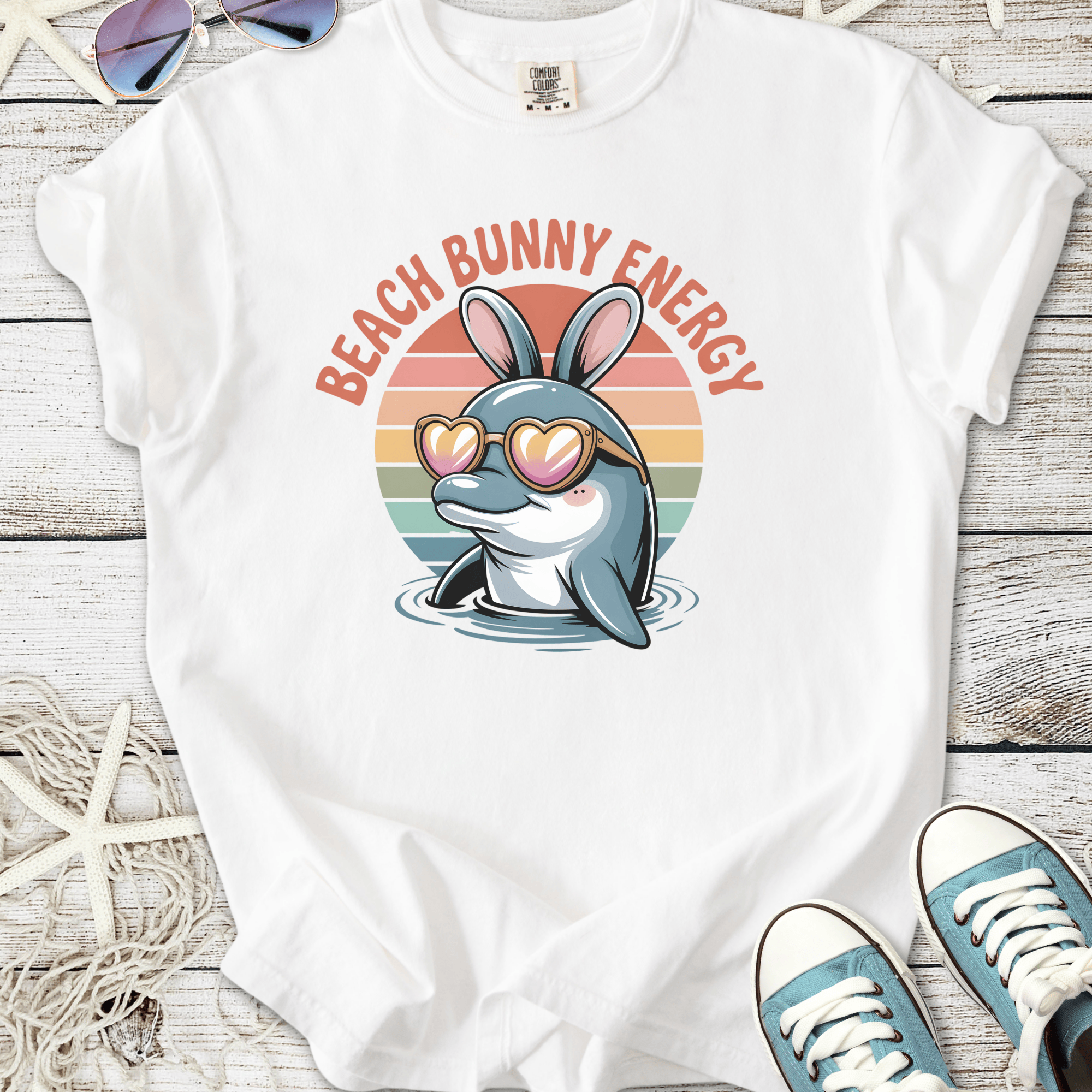 White t-shirt with a dolphin wearing bunny ears and sunglasses, featuring 'Beach Bunny Energy' text.