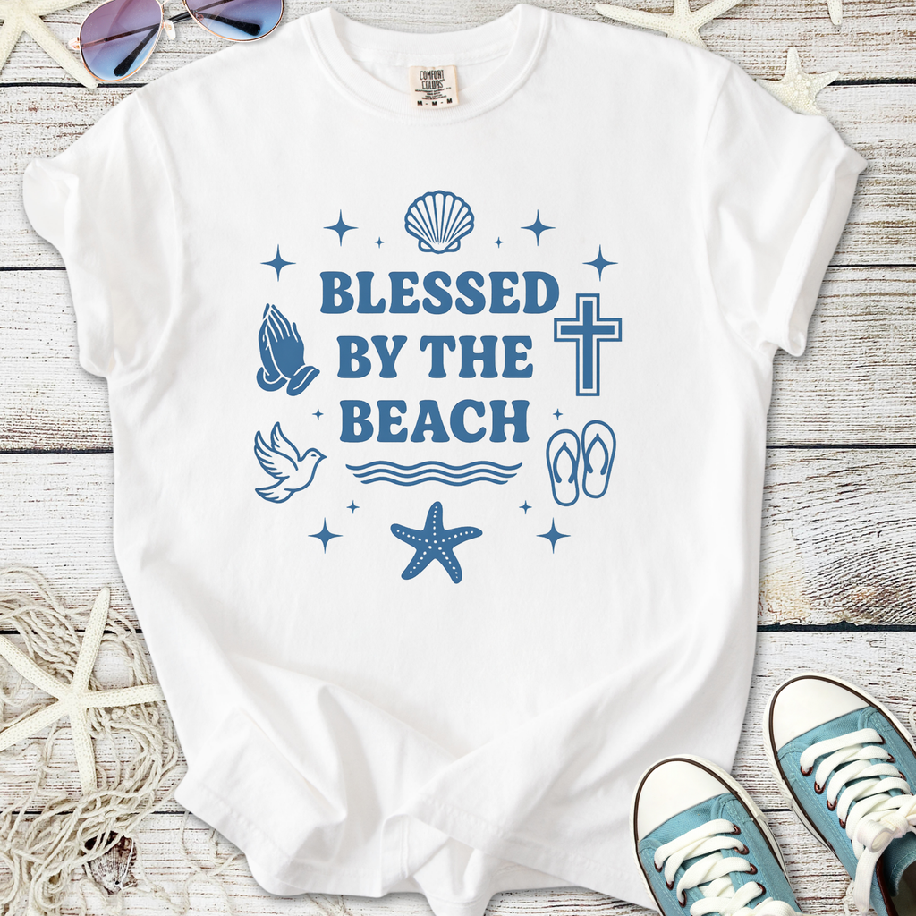 White t-shirt featuring 'Blessed By The Beach' graphic, sea-themed designs, perfect for summer style.
