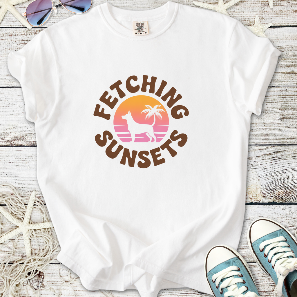 White t-shirt featuring 'Fetching Sunsets' graphic with dog silhouette and palm trees, perfect for summer.