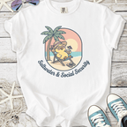 White t-shirt featuring playful sunbathing character with palm trees, captioned 'Saltwater & Social Security'.