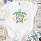 White t-shirt featuring a colorful turtle design with floral patterns, perfect for casual wear.