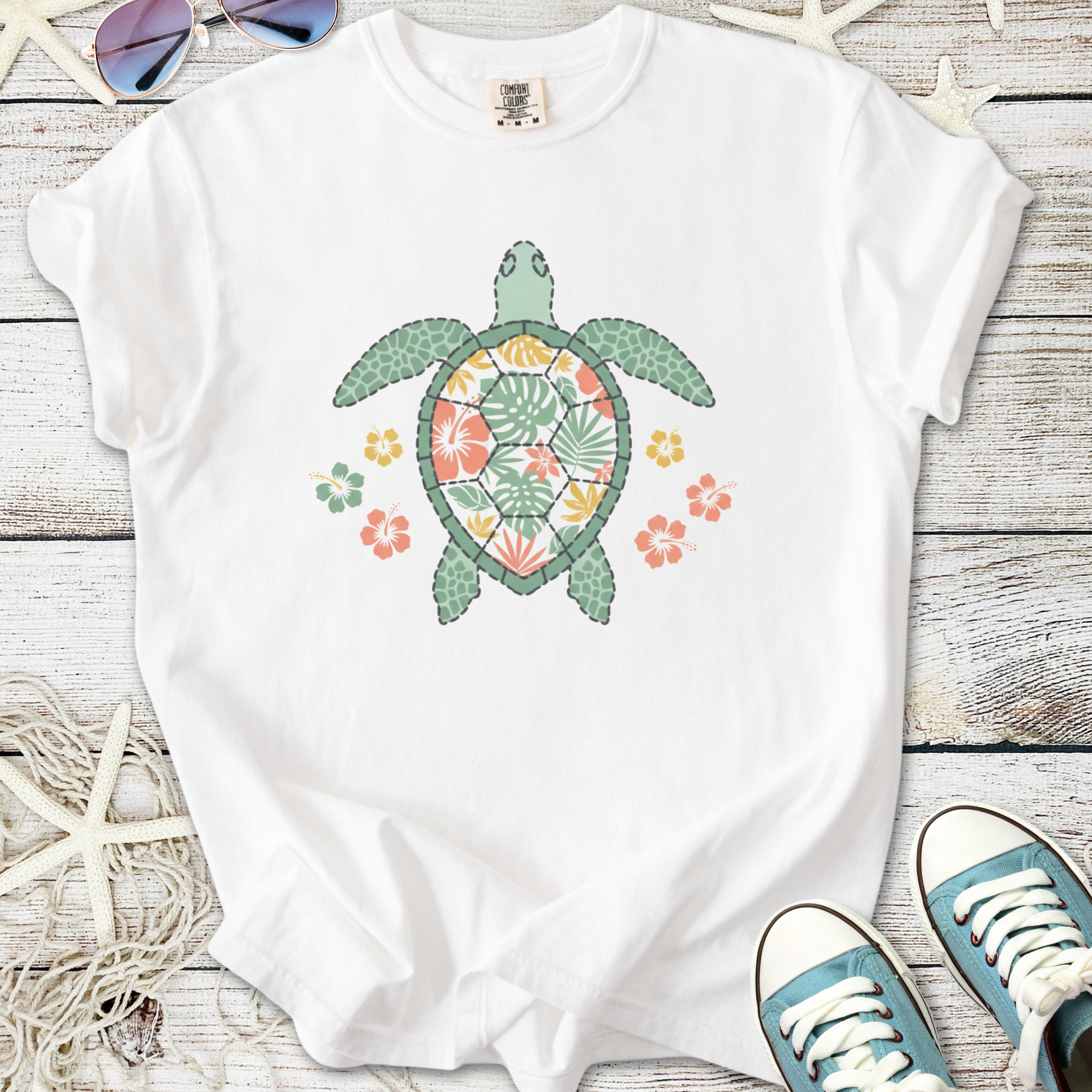 White t-shirt featuring a colorful turtle design with floral patterns, perfect for casual wear.