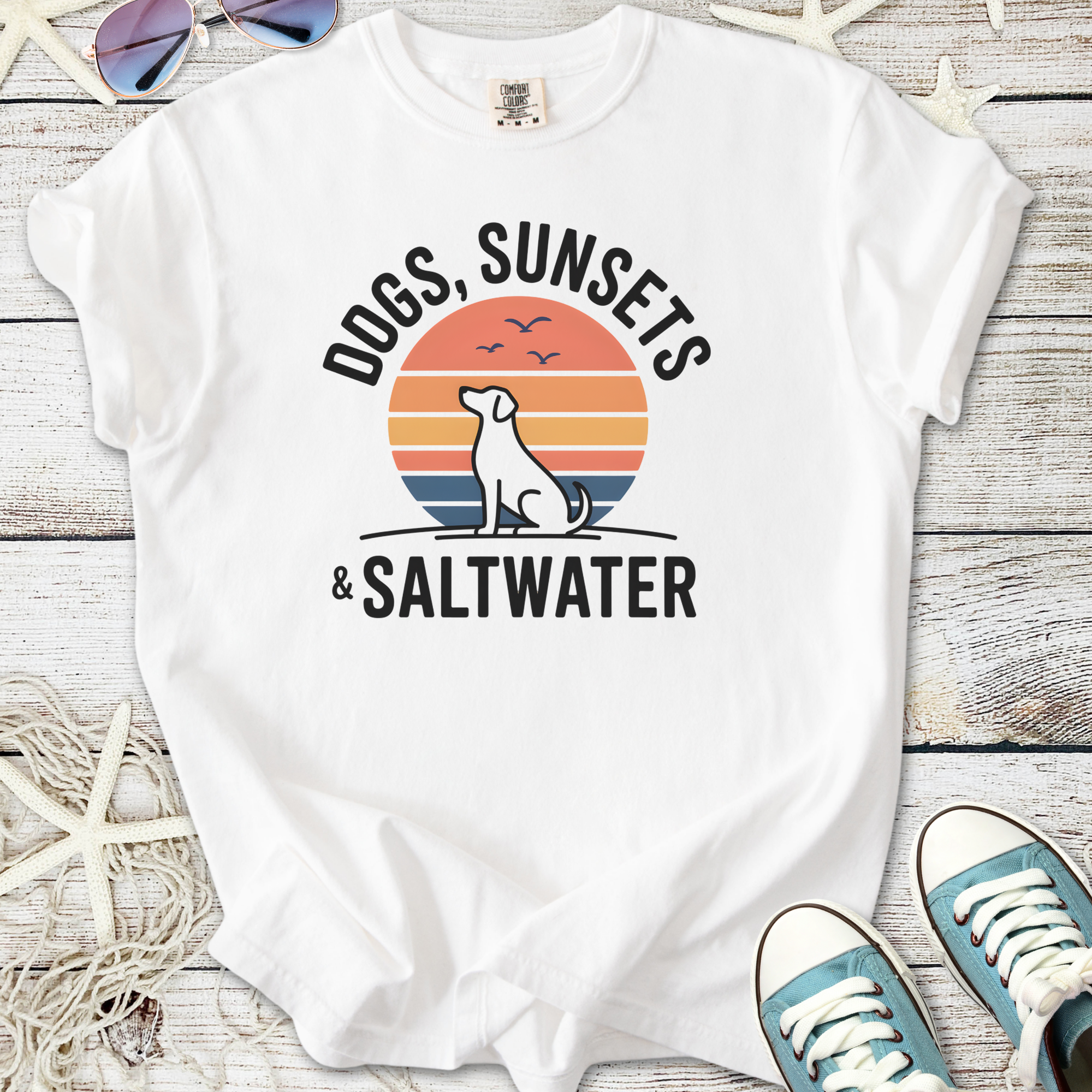 White t-shirt with 'Dogs, Sunsets & Saltwater' graphic, featuring a dog silhouette and sunset design.