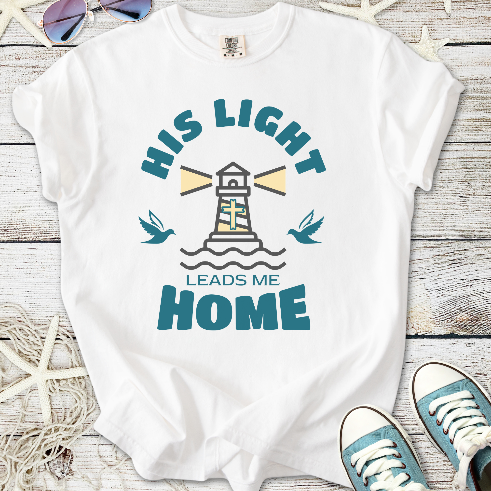 White t-shirt with lighthouse and birds design, features 'His Light Leads Me Home' graphic.