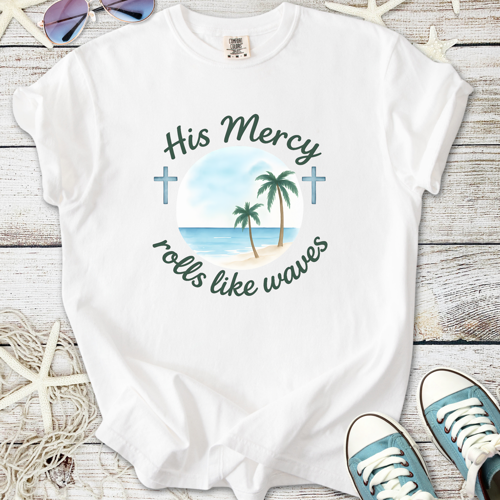 White t-shirt with palm tree and cross design, featuring 'His Mercy rolls like waves' text.