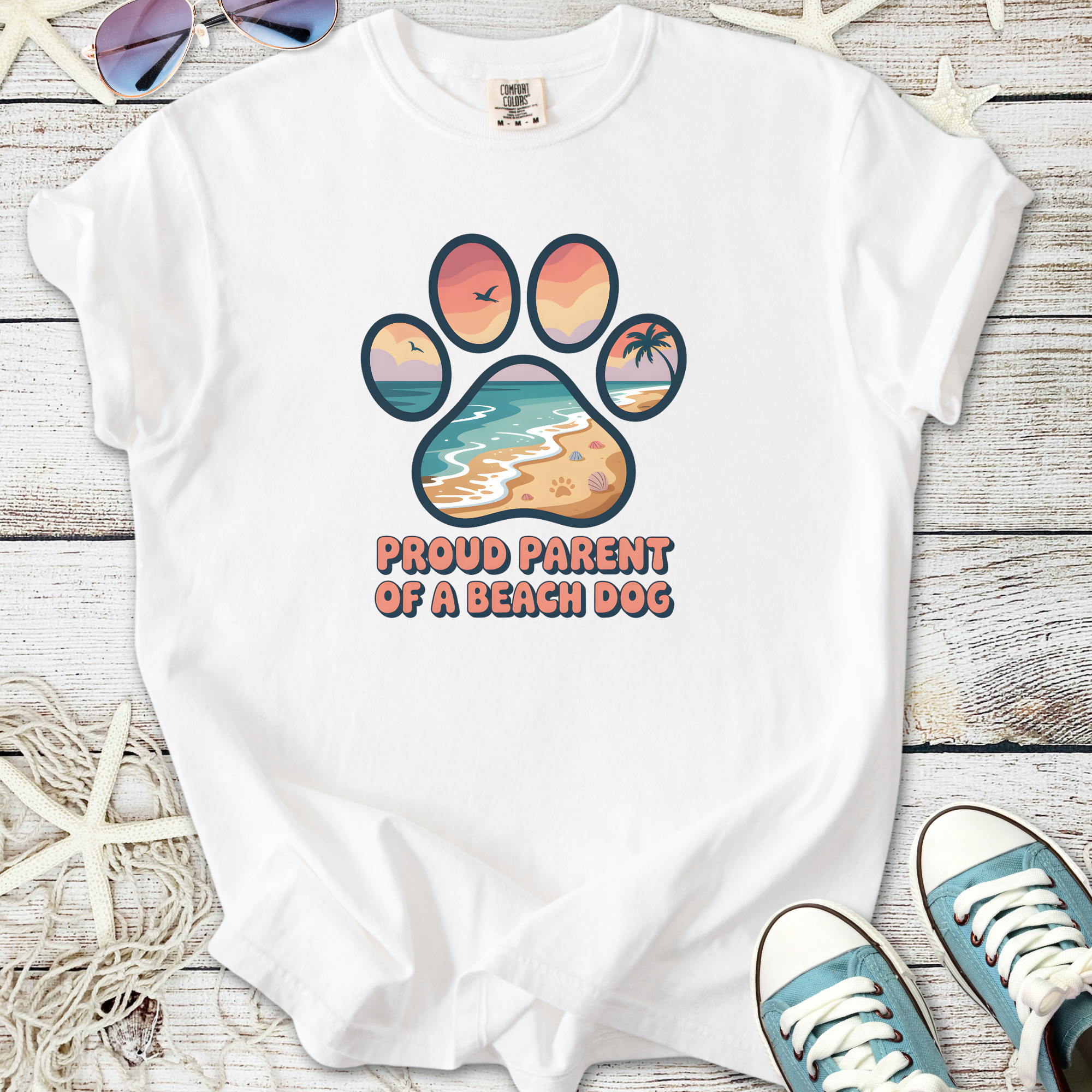 White t-shirt featuring 'Proud Parent of a Beach Dog' graphic with a beach-themed paw print design.