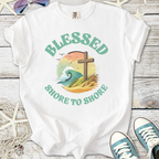 White graphic tee with 'Blessed Shore to Shore', featuring ocean wave and cross design.