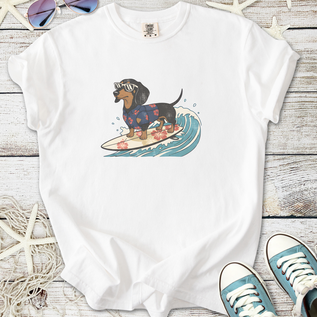 White t-shirt featuring a dachshund surfing with sunglasses in a floral shirt, perfect for dog lovers.